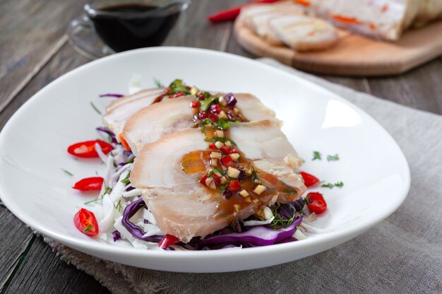 Pork belly with cabbage salad in a white bowl on a wooden background. Chinese cuisine.