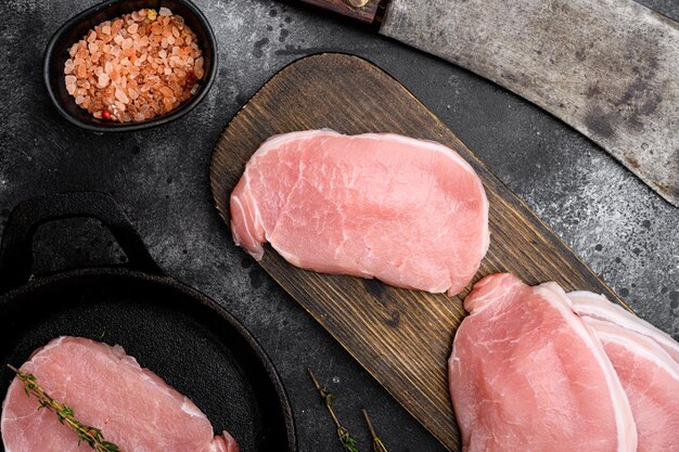 검은색 돌 탁자 배경에 있는 돼지고기 얇게 썬 신선한 고기 세트, 평면도