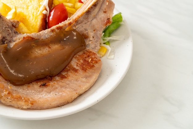 Pork chop steak with chips and mini salad on white plate