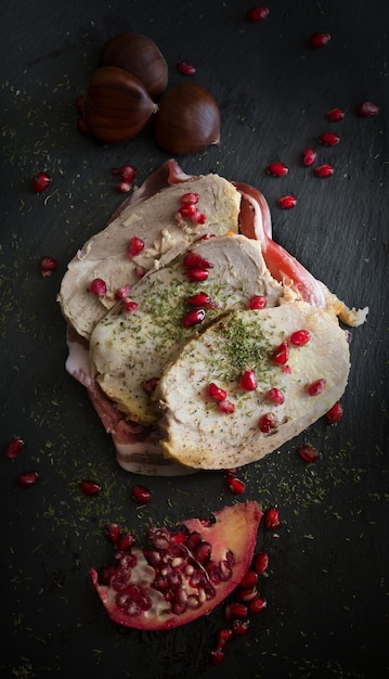 Pork chops cooked in pan with oil and pomegranate seeds on slate dish