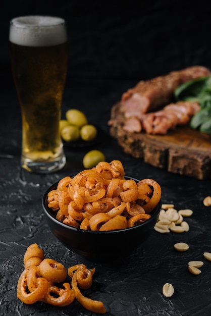 Spuntino dell'orecchio di maiale nella ciotola si chiuda con la birra in un bicchiere