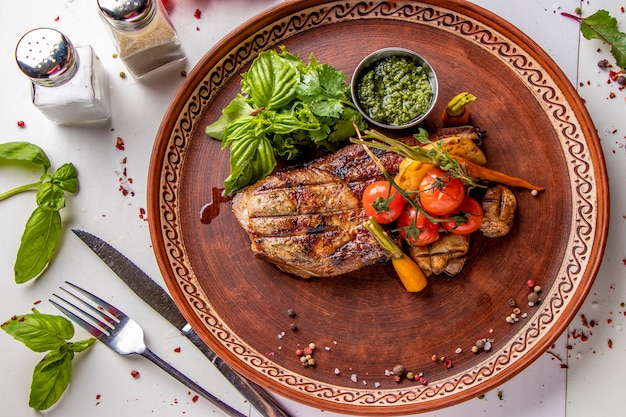 Pork entrecote served with grilled vegetables, mushrooms and pesto sauce, restaurant dish, Top view, Horizontal orientation