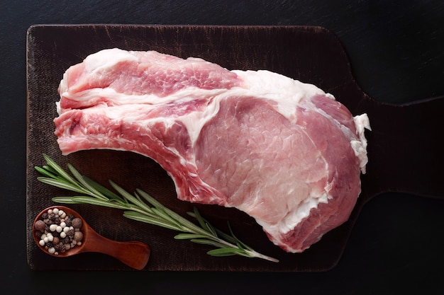 Pork entrecote with rosemary on a black background with a spoon of pepper