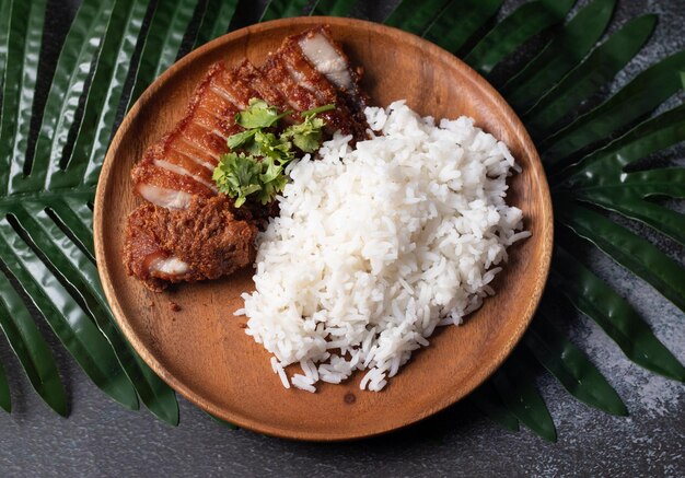 Свиной жареный рис на темной деревянной тарелке