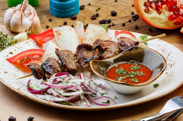 Pork kebabs on a plate with sauce on a wooden table