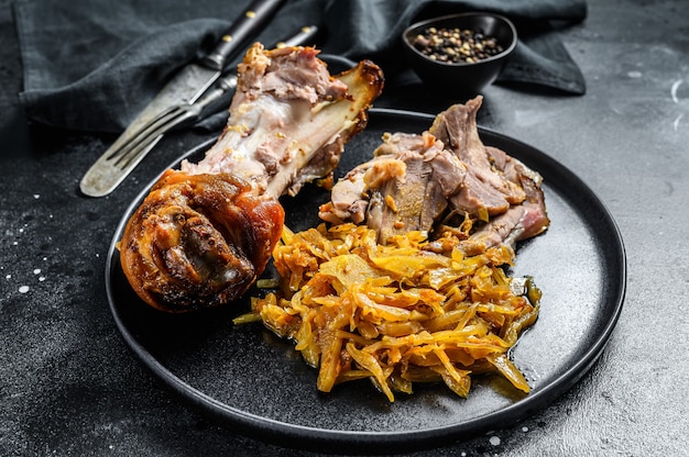 Pork leg eisbein with braised cabbage. Black background. Top view.