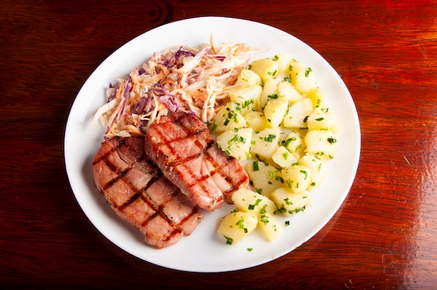 Pork loin meal coleslaw salad and boiled potatoes with green onions top view