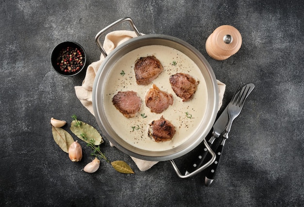 Pork meat medallions with cream sauce in skillet