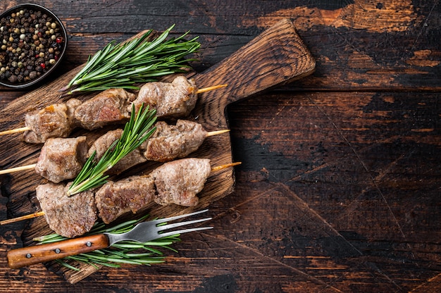 Pork meat Shish kebab on skewers with herbs  on a wooden board