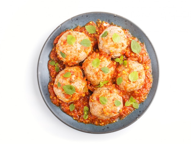 Pork meatballs with tomato sauce oregano leaves spices and herbs on blue ceramic plate isolated on white background