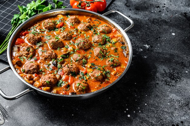 Pork meatballs with tomato sauce and vegetables in a pan