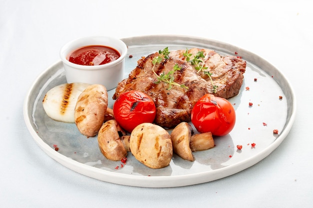 Pork medallions with grilled vegetables on white background