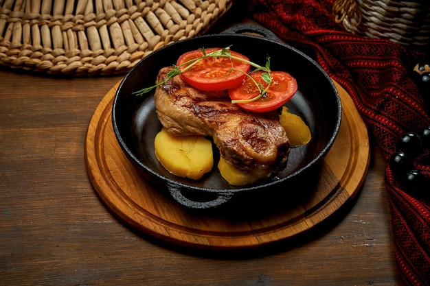 Pork medallions with a side dish of potatoes in a pan Pork steak on a wooden background