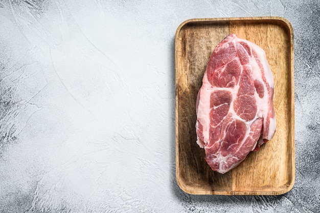 Pork neck piece on brown wooden chopping board