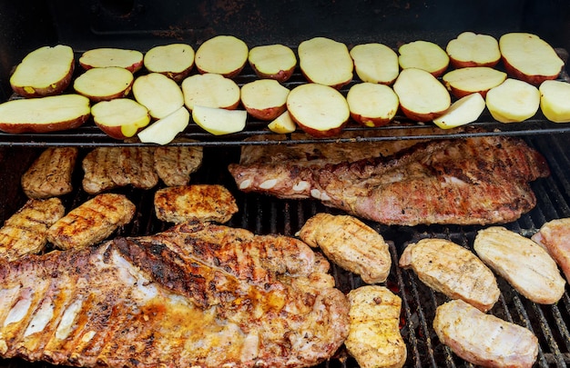 Bistecca di costolette di maiale sulla griglia del barbecue caldo con fiamme luminose sullo sfondo da vicino