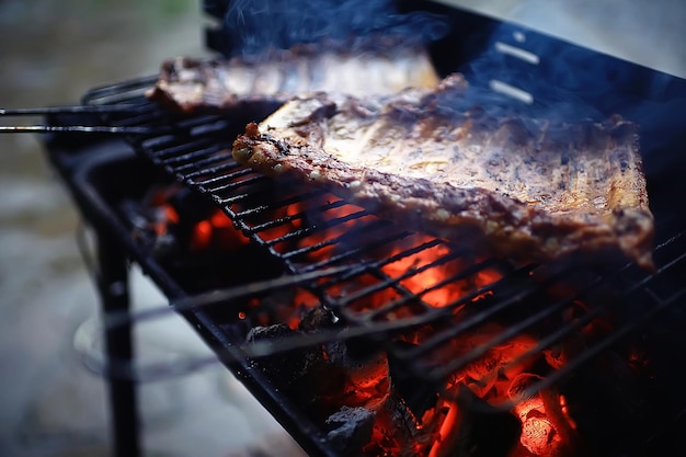 Photo pork ribs on the grill cooking coals / fresh meat pork cooked on charcoal, summer home cooked meal, grilled ribs