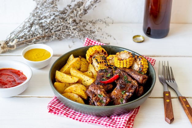 Costine di maiale con patate su un tavolo di legno. barbecue. griglia. cucina americana. ricetta.