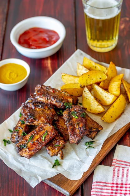 Pork ribs with potatoes on a wooden table. Barbecue. Grill. American cuisine. Recipe.