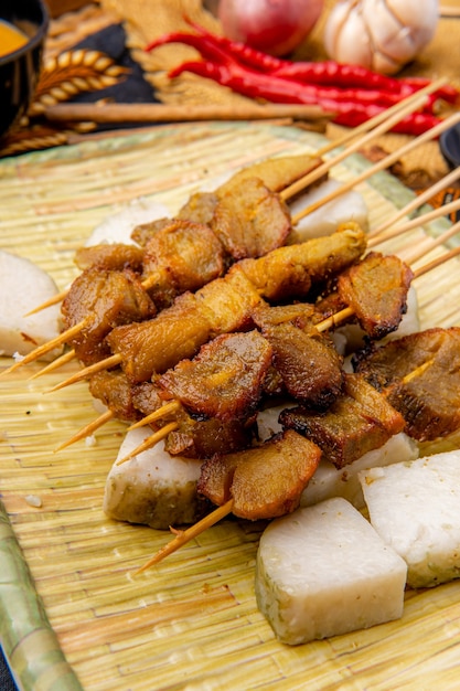 Pork Satay 또는 Sate Babi Pork Satay는 매콤한 파당 소스와 바왕 고렝 바삭 바삭한 튀긴 샬롯을 뿌린 론통 또는 케 투팟 떡 조각과 함께 제공됩니다.