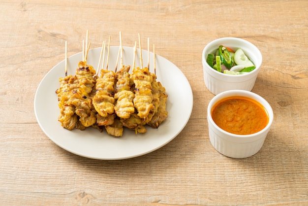 Pork satay with peanut sauce pickles which are cucumber slices and onions in vinegar - Asian food style