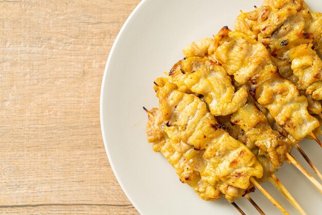 Satay di maiale con sottaceti di salsa di arachidi che sono fette di cetriolo e cipolle in aceto - stile di cibo asiatico