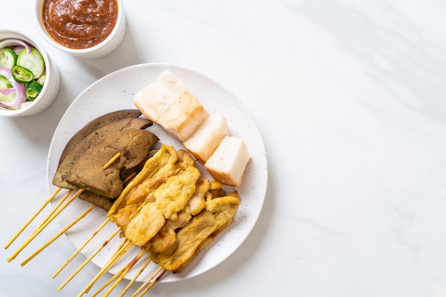 Pork Satay with your Peanut Sauce  and pickles which are cucumber slices and onions in vinegar