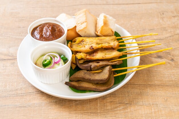 Pork Satay with your Peanut Sauce  and pickles which are cucumber slices and onions in vinegar