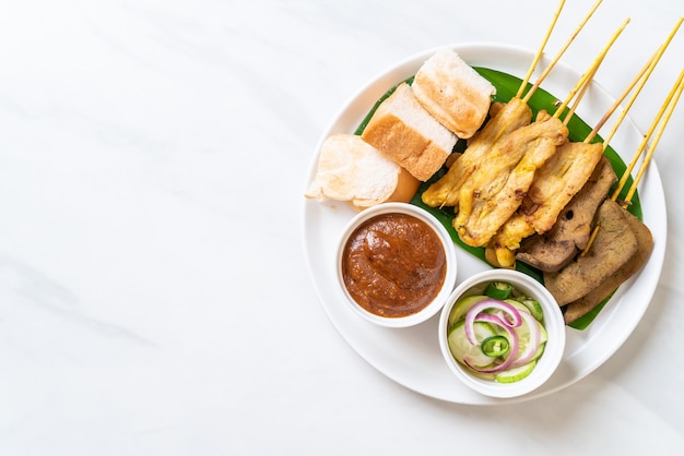 Pork Satay with your Peanut Sauce  and pickles which are cucumber slices and onions in vinegar
