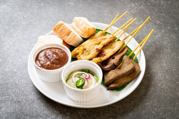 Pork Satay with your Peanut Sauce  and pickles which are cucumber slices and onions in vinegar