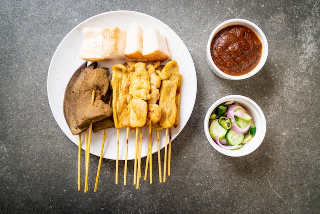 Pork Satay with your Peanut Sauce  and pickles which are cucumber slices and onions in vinegar