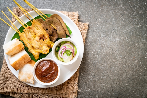 Pork Satay with your Peanut Sauce  and pickles which are cucumber slices and onions in vinegar