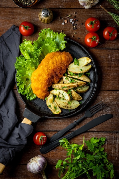 Pork schnitzel with baked potatoes in a pan