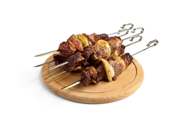 Pork shish kebab skewers on wooden cutting board isolated on white background.