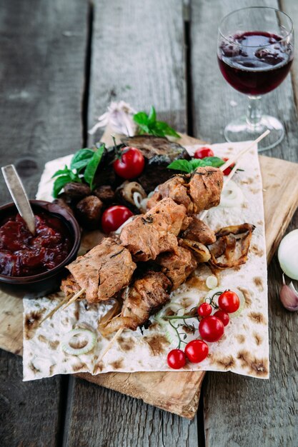 Pork shish kebab with vegetables and tomato sauce closeup on a wooden table