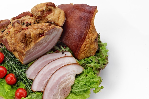 Photo pork smoked bacon with green lettuce garlic tomatoes and rosemary on a white background