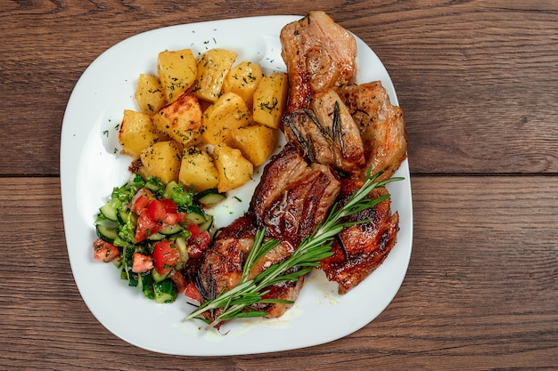 Pork steak, baked potatoes, salad and a sprig of rosemary. 