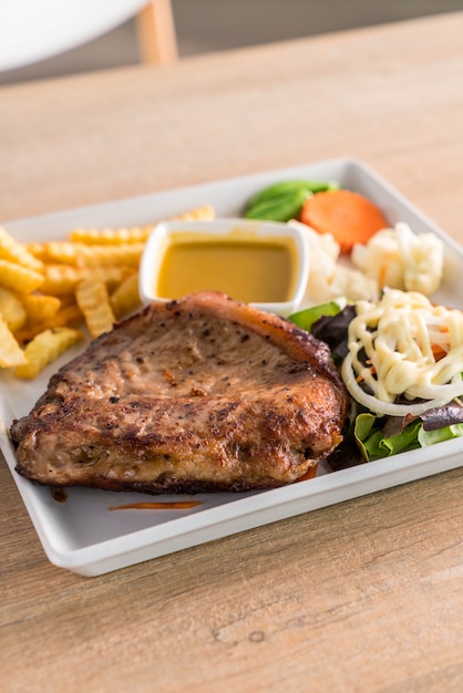 Bistecca di maiale con patatine fritte e insalata