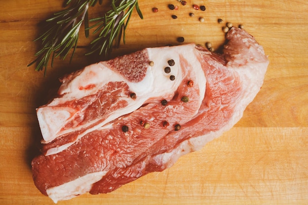 Pork steak with rosemary and pepper on a wooden background Raw meat steak vintage photo processing