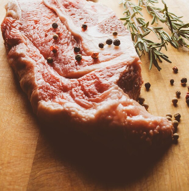 Pork steak with rosemary and pepper on a wooden background Raw meat steak vintage photo processing