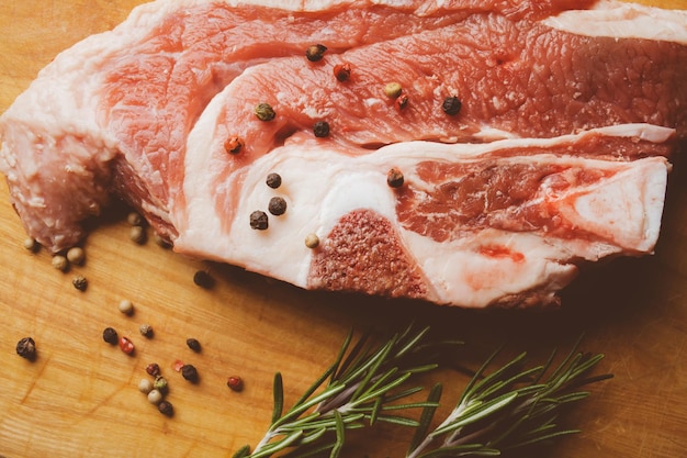 Pork steak with rosemary and pepper on a wooden background Raw meat steak vintage photo processing