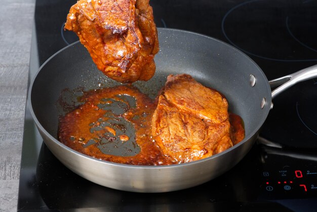 Pork steak with sauce fried in a frying pan