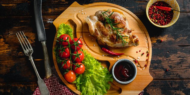 Pork steak on a wooden board with cherry tomatoes and salad rustic food