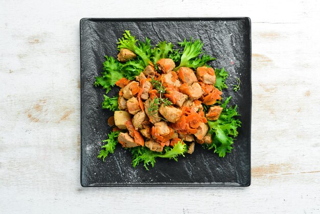 Pork stewed with vegetables in beer on a black stone plate Top view Old background rustic style