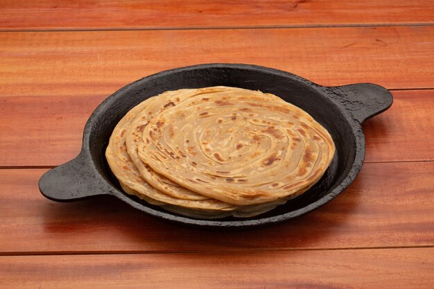 Porotta of lachha paratha gelaagd plat brood gemaakt van tarwebloem in een gietijzeren pan