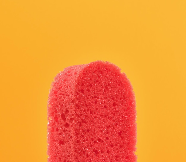Porous sponge shower red color on yellow bright background skincare and beauty bathroom routine