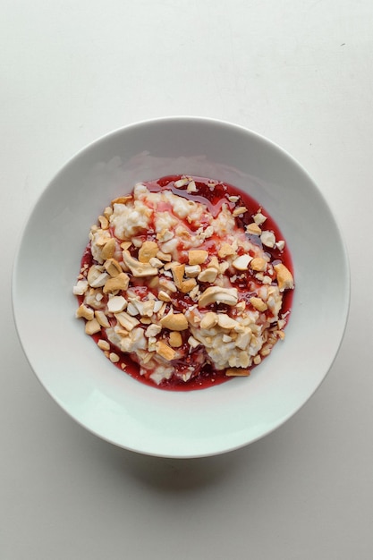 Porridge con marmellata e noci su un piatto bianco su sfondo bianco