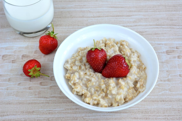 porridge with strawberry and milk in the white bowl, close-up