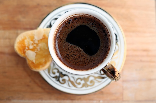 Porseleinen kopje traditionele Turkse en Ottomaanse koffie met een koekje op een houten serveerplank