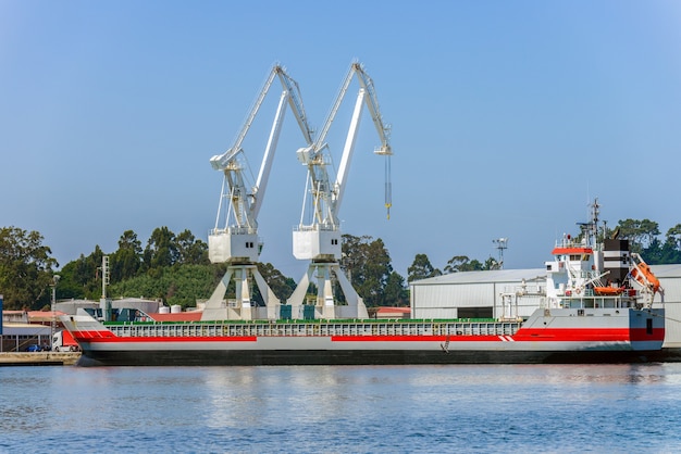 写真 港湾に産業貨物船を積み込むポートクレーン