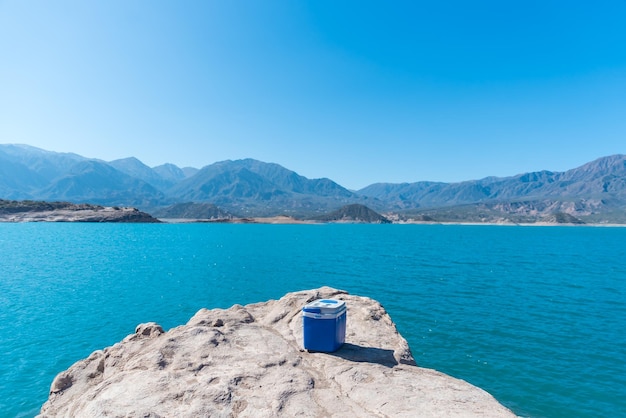Portable cooler on the rocks lake between mountains